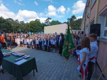 Grupa uczniów stoi przed budynkiem szkoły