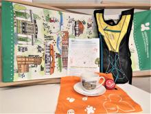 Gadżety gminne - plecak, koszulka, filiżanka, dzwonek leżą na stole