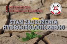 Grafika wektorowa informująca o wprowadzeniu stanu zagrożenia hydrogeologicznego. Napis na tle wyschniętej gleby.