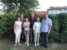 grupka osób stoi na tle krzaków 