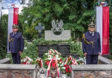 Dwóch strażników miejskich pełni wartę przy nagrobku na cmentarzu.
