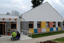 budynek z kolorowymi namalowanymi kwadratami, przed budynkiem kobieta z wózkiem