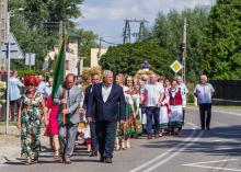 Grupa osób maszerująca środkiem drogi.