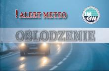 Zdjęcie przedstawia meteorologiczne ostrzeżenie o oblodzeniu dróg z napisem „alert meteo” oraz „oblodzenie” na tle zimowej, śliskiej drogi, na której widać samochody z włączonymi światłami.