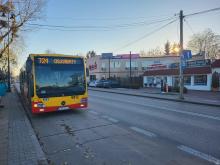 Autobus linii 724 z napisem OS. KABATY stojący na ulicy w pobliżu punktów usługowych i sklepów.