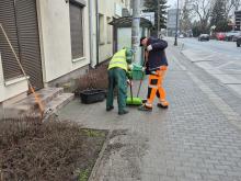 Dwie osoby sprzątają chodnik.