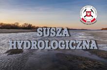 Wysychające koryto rzeki przy zachodzie słońca, z widocznymi płyciznami i osadami, opatrzone napisem „Susza hydrologiczna” oraz logo Państwowego Instytutu Geologicznego.
