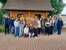 wycieczka szkolna, przed drewnianym budynkiem i kamiennym pomnikiem