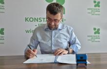 Uśmiechnięty mężczyzna podpisuje dokumenty.