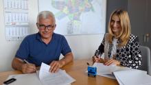 Kobieta i mężczyzna siedzą przy stole i podpisują dokumenty.