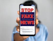 Osoba trzymająca telefon z napisem Stop Fake News