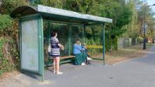 Osoby czekające na przystanku autobusowym.