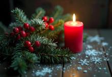 stroik świąteczny z zielonych gałązek choinki i zapalonej czerwonej świeczki