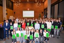 Uczestnicy gali sportowej wraz z burmistrzem Michałem Wiśniewskim pozują do wspólnego zdjęcia zbiorowego.