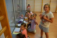 Zdjęcie grupy uśmiechniętych dzieci rysujących w sali gimnastycznej.