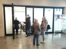 Grupa osób stoi przed wejściem do sali