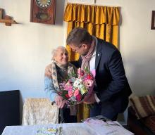 mężczyzna w garniturze składa życzenia starszej kobiecie