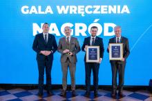 Na scenie gali wręczenia nagród przedstawiciele samorządów pozują z dyplomami i statuetką przy tle z napisem „Gala wręczenia nagród”.