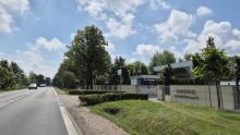 Droga wojewódzka przebiegająca przez zalesiony teren z poboczem, przy którym planowana jest budowa infrastruktury rowerowo-pieszej.