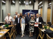 Grupa uczestników posiedzenia Parlamentarnego Zespołu ds. Seniorów pozuje do wspólnego zdjęcia w sali obrad.