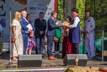Na scenie przedstawiciele samorządu odbierają od starostów bochen chleba. 