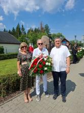 Trzyosobowa delegacja Rady Seniorów Gminy Konstancin-Jeziorna – Alfreda Konopka, Wojciech Guszkowski i Grzegorz Rutkowski – stoi z wieńcem biało-czerwonych goździków przed pomnikiem pamięci z symbolem Polski Walczącej podczas obchodów rocznicy Powstania Warszawskiego.