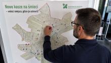 Mężczyzna przypina kolorową pinezkę do mapy gminy Konstancin-Jeziorna, wskazując proponowaną lokalizację nowego kosza na śmieci.