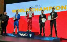 Kamil Kraczkowski , reprezentant Polski, odbiera złoty medal podczas ceremonii dekoracji na Mistrzostwach Świata WAKO. Zawodnicy stoją na podium na tle wielkiego ekranu z napisem "WAKO WORLD CHAMPION".