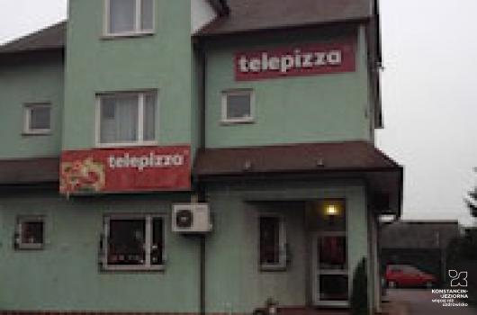 Pietrowy budynek z dwuspadowym dachem, od frontu widoczne szyldy Telepizza, ściany budynku jasnozielone