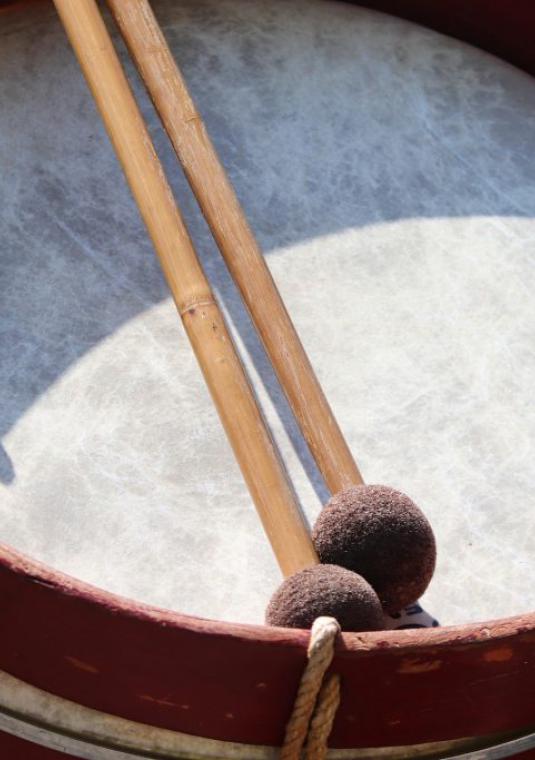 Instrument muzyczny: bęben. Na nim leżą dwie pałki do wybijania rytmu.