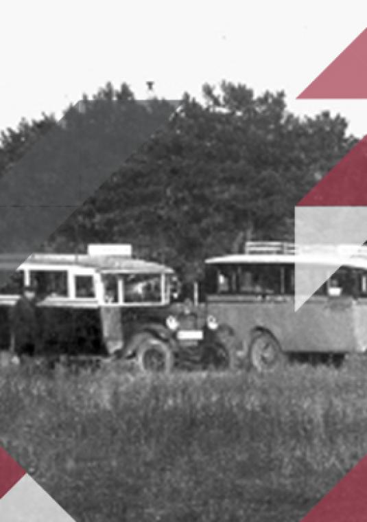 Stylizowane, czarno-białe zdjęcie 4 autobusów sprzed Drugiej Wojny Światowej. Stoją zaparkowane na łace. W tle ściana lasu. 