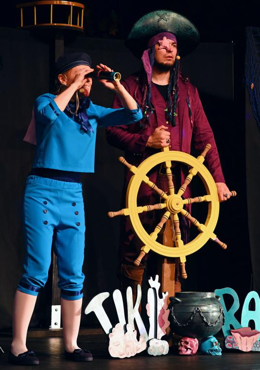 Na scenie dwóch aktorów przebranych w strój piracki. Jeden z nich trzyma w ręku koło sterowe, drugi patrzy przez lornetkę.
