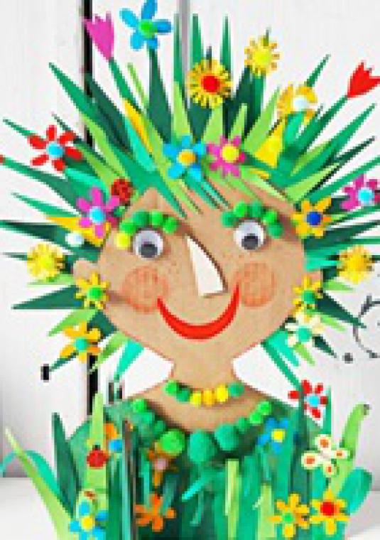 Narysowana uśmiechnięta buzia, z włosami i ubraniem z zielonej trawy i kolorowych kwiatów.