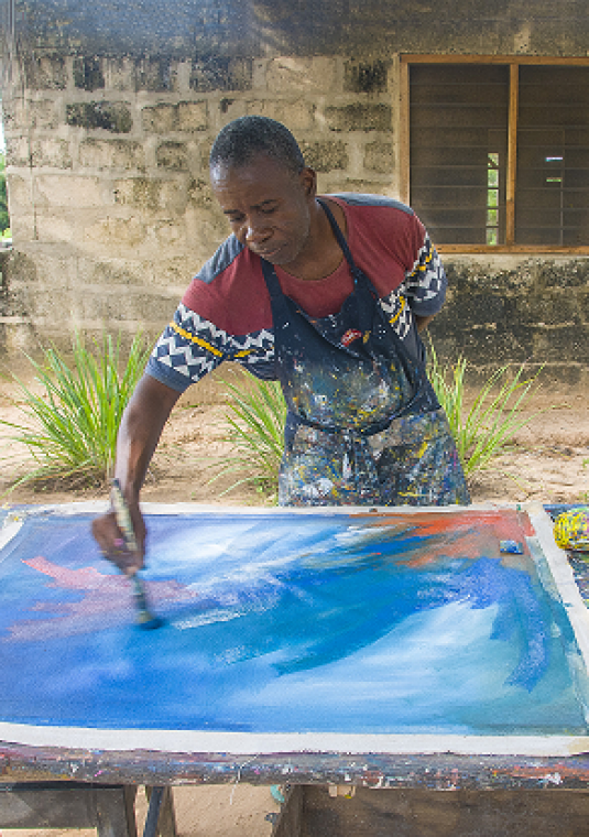 Afroamerykanin maluje obraz farbami. 