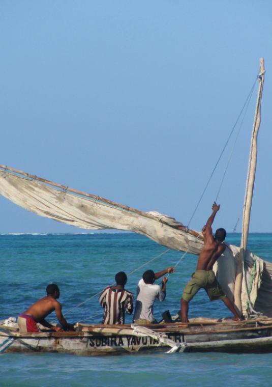 Czworo męzczyzn na niedużej łodzi. W tle widac drugą łódkę. Ocean jest spokojny, a niebo bezchmurne.