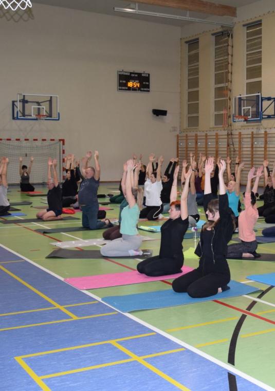 sala gimnastyczna a w niej ćwiczą osoby na matach