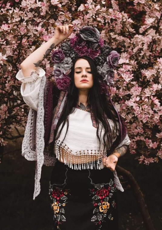 Wokalistka Marta Bejma na tle różowych kwiatów.