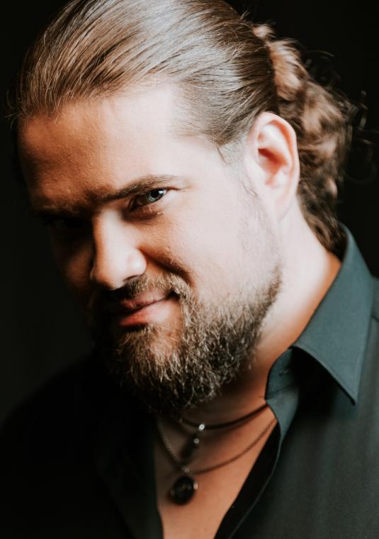 Zdjęcie portretowe Macieja Szulca na czarnym tle.