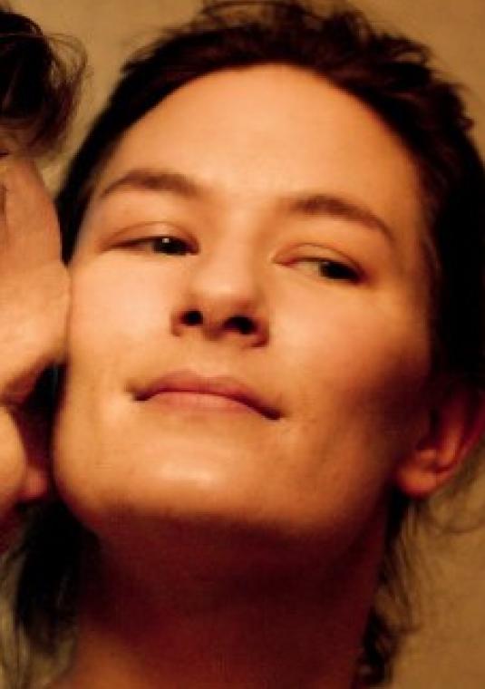 kadr z filmu Być kochaną - duże zbliżenie na twarze kobiety i mężczyzny, ciepłe odcienie, uśmiechnięci, intymny moment przytulenia