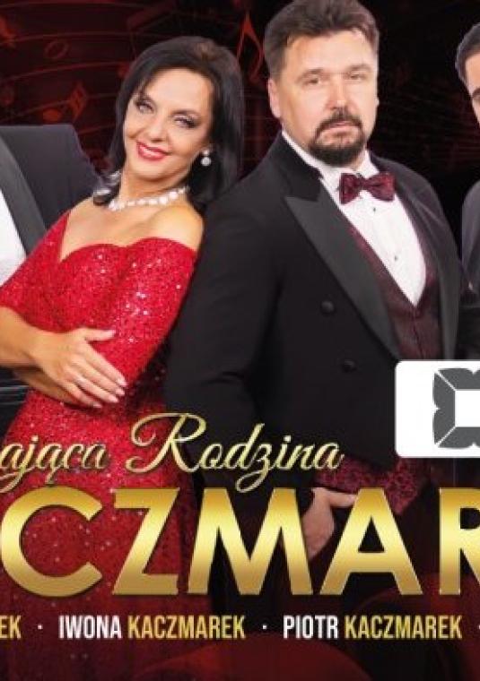 Plakat promocyjny koncertu. Przedstawia czteroosobowy zespół Śpiewająca Rodzina Kaczmarek: mężczęzn w eleganckich garniturach i smokingach oraz kobietę w czerwonej, błyszczącej sukni balowej. Na pierwszym planie widnieje złoty napis „Śpiewająca Rodzina KACZMAREK” wraz z imionami artystów (Wojciech, Iwona, Piotr, Adam). W prawym rogu znajduje się logo Konstancińskiego Domu Kultury.