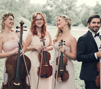 Zdjęcie grupowe kwartetu smyczkowego. Obok siebie stoją trzy kobiety ubrane w jasne sukienki i jeden mężczyzna w garniturze. Każdy w rękach trzyma skrzypce. 