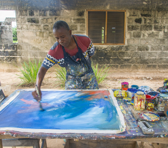 Afroamerykanin maluje obraz farbami. 