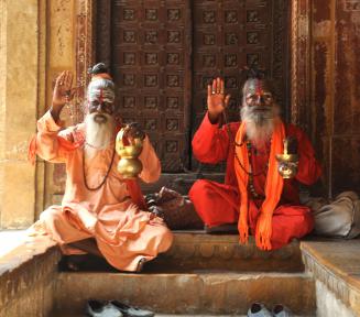 Zdjęcie. Dwóch starczych panów w pomarańczowych strojach siedzi na podłodze. 