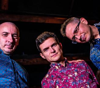 Trzech mężczyzn w kolorowych koszulach z zespołu Tubis Trio - patrzą w dół.