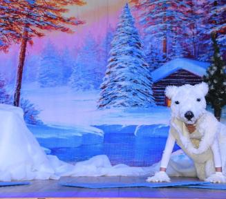 Osoba przebrana za niedźwiedzia polarnego na tle ośnieżonego lasu.